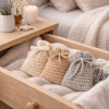 Three hand-crocheted lavender bags resting on a soft blanket inside a wooden drawer, creating a calm and comforting bedroom scene.